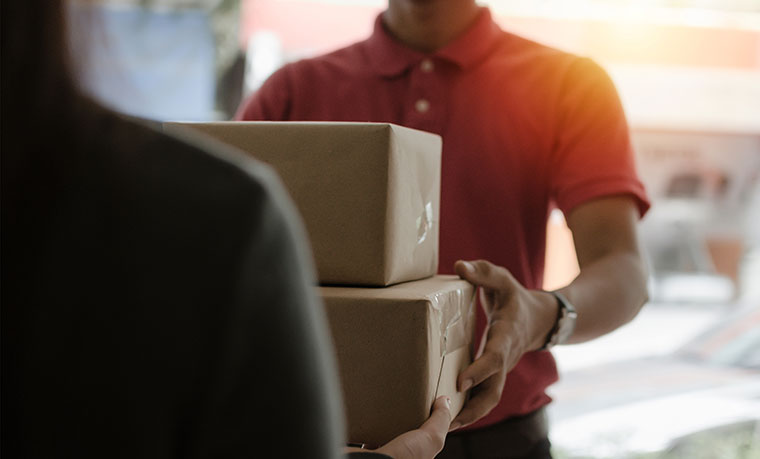 Home delivery service man in red uniform handing parcel boxes to recipient
